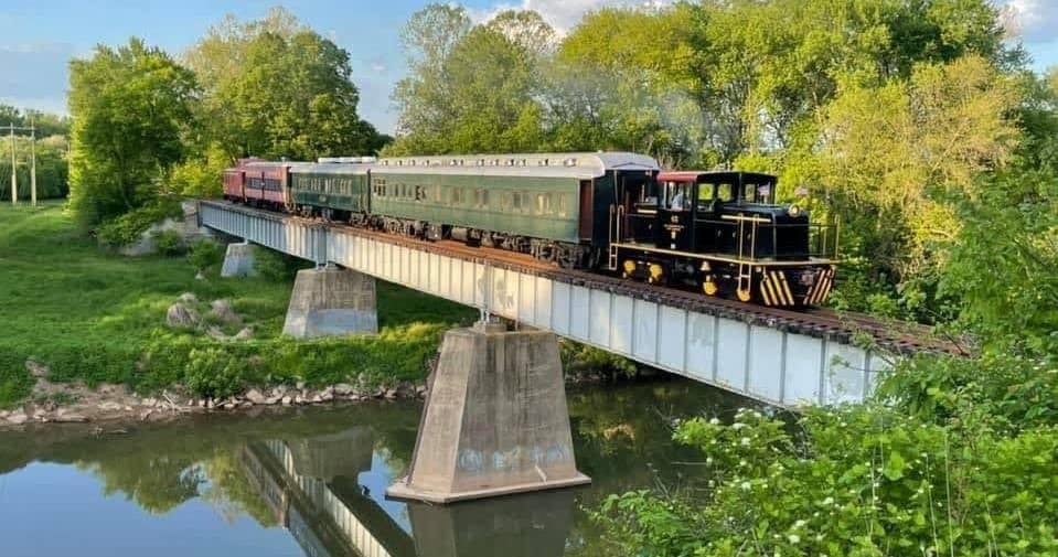 Vintage train crossing river bridge on scenic countryside ride