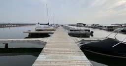 Wooden marina dock leading to lake horizon at sunrise