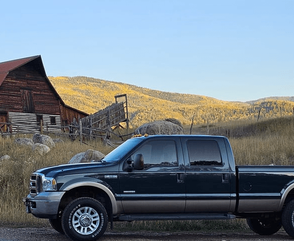 Pickup truck parked near rustic barn and mountain hills