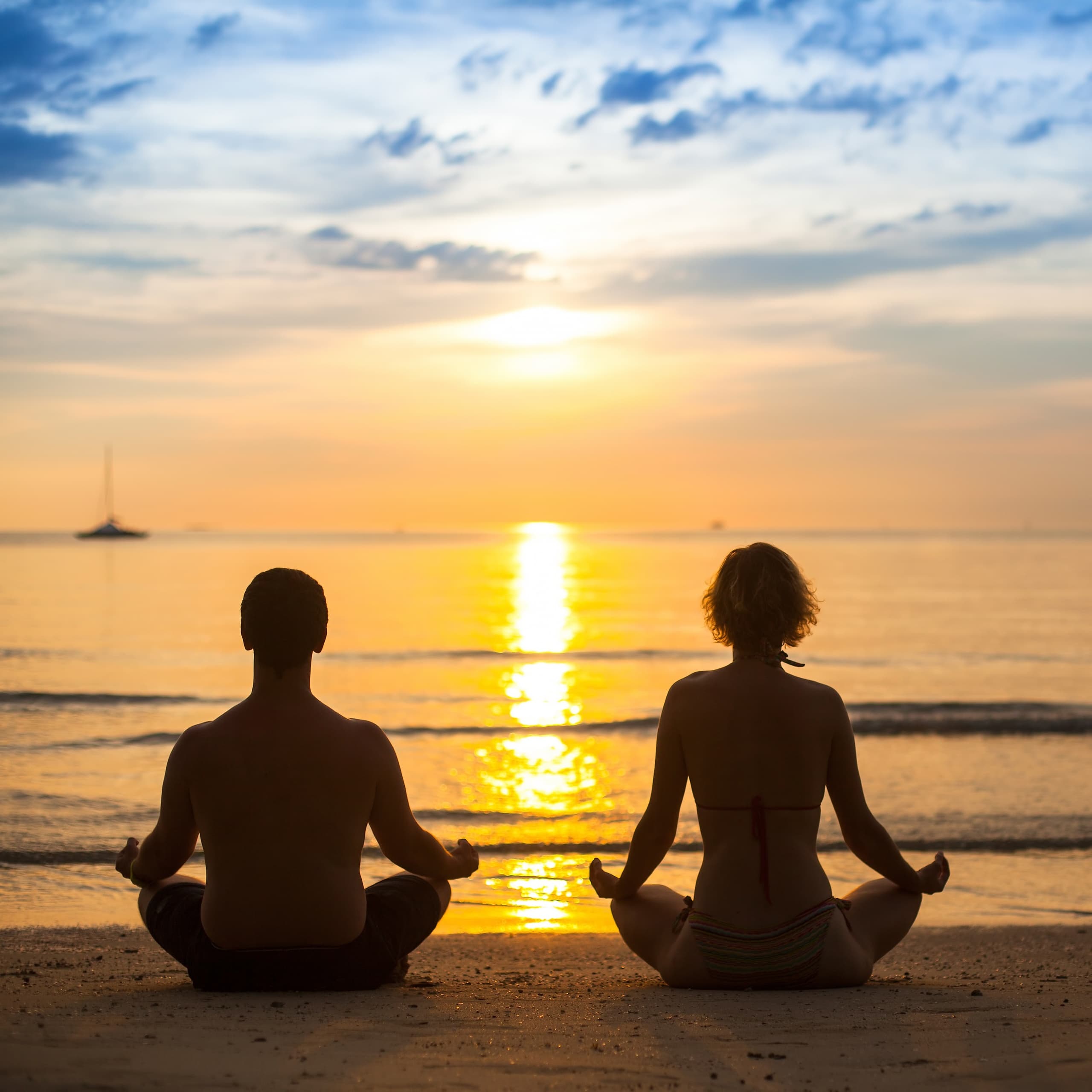 Couple meditating at sunset on a tranquil ocean beach