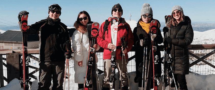 Ski group posing on snowy summit with clear alpine panoramas