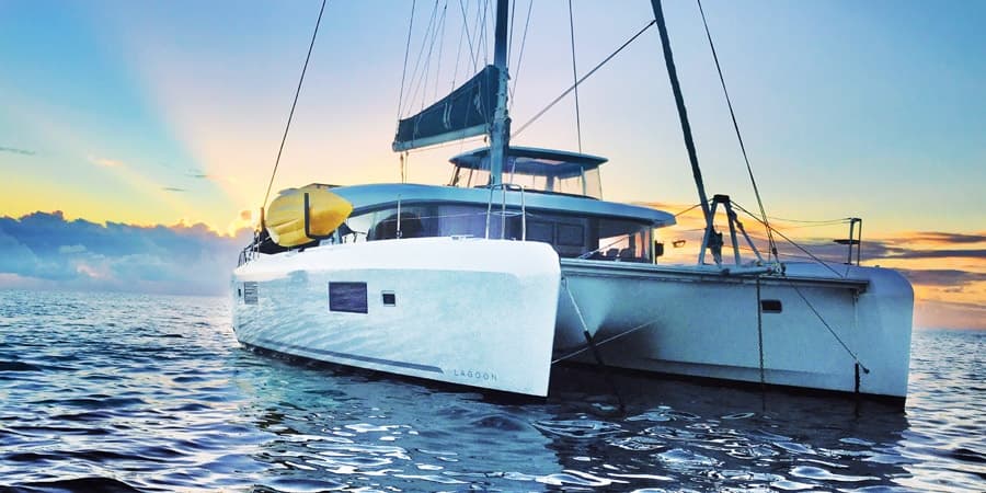 Catamaran anchored at sunset on open ocean, luxury sailing cruise