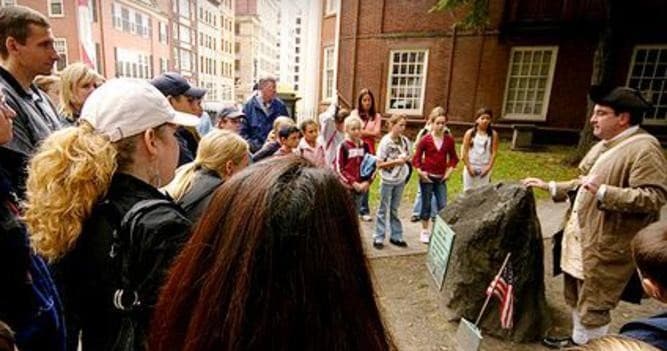Tour guide speaking to crowd at historic Boston site on walking tour