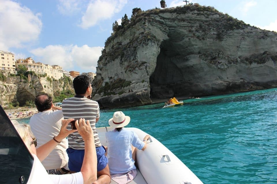 Passengers boating toward coastal caves and cliffs