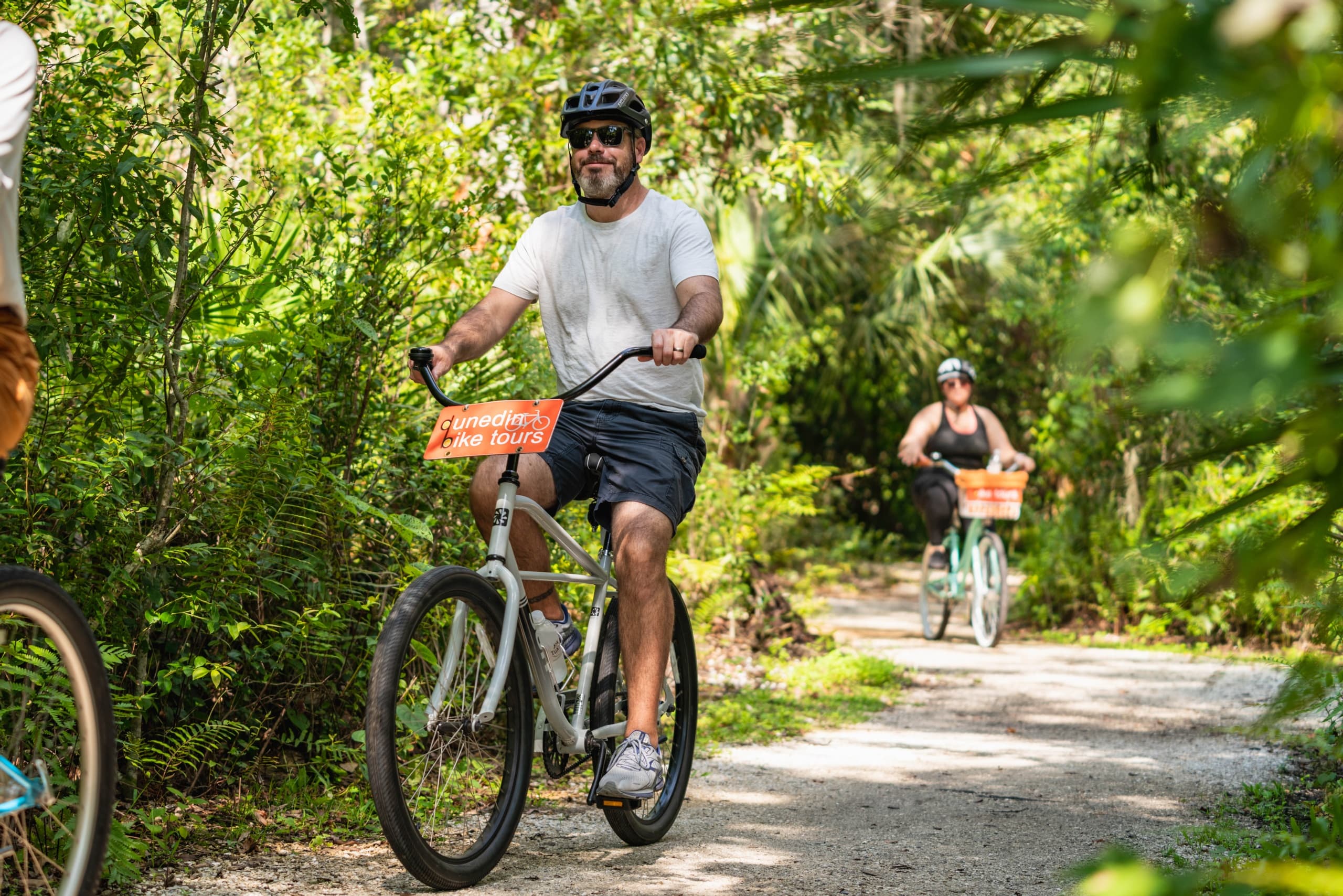Cyclists on shaded coastal woodland trail in Dunedin bike tour