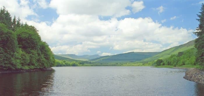 Calm lake between wooded hills under clouds for peaceful boating