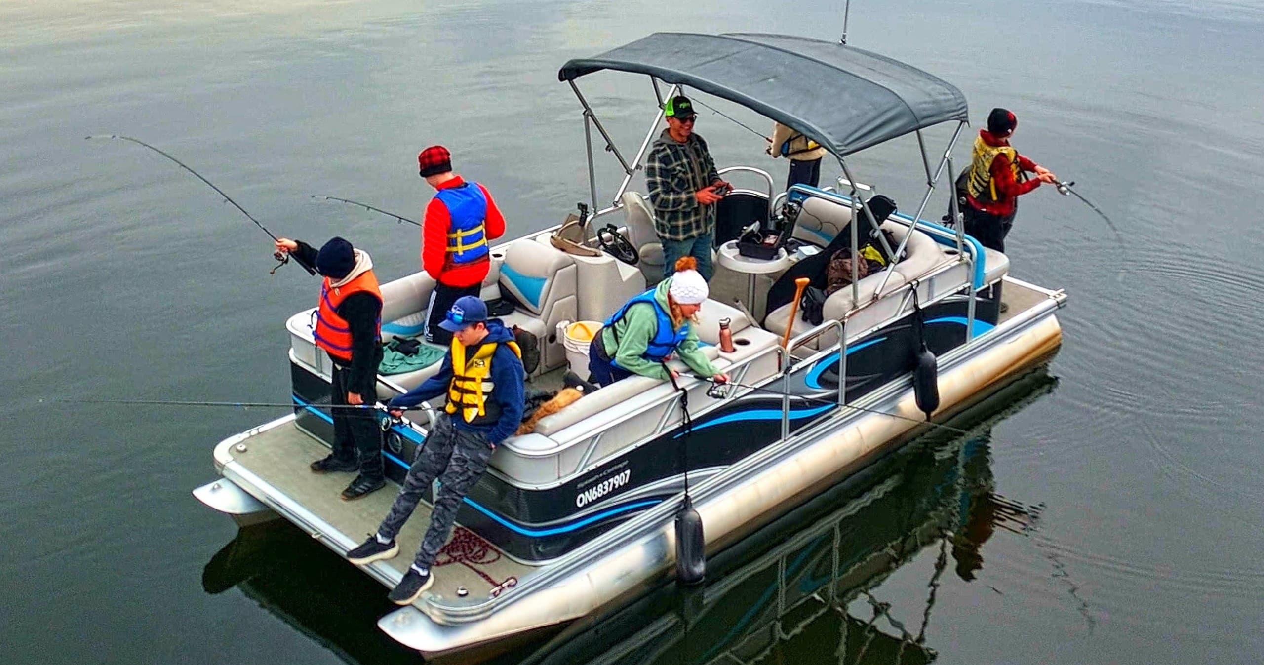 Family fishing from pontoon boat on open lake, group angling trip