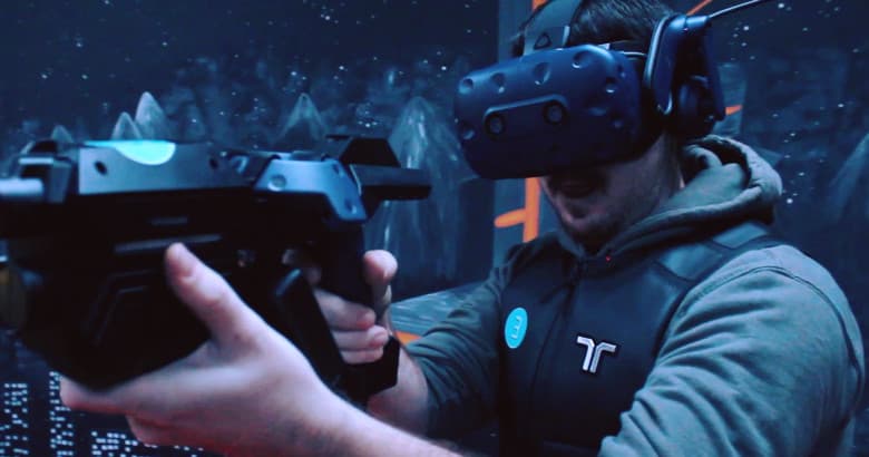 Player in VR shooter arena wielding gun in indoor virtual combat