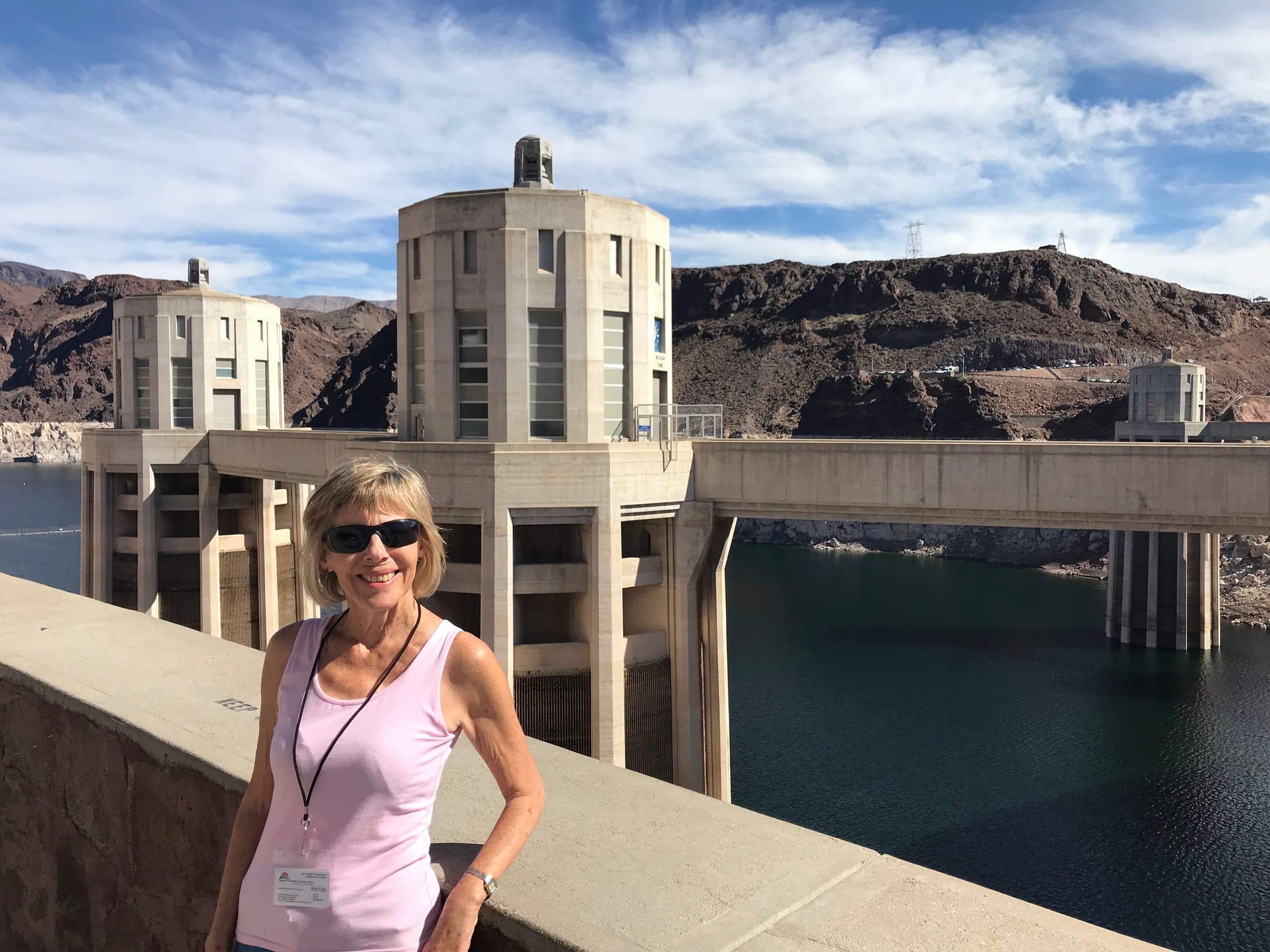 Visitor posing at large dam overlooking reservoir and canyon