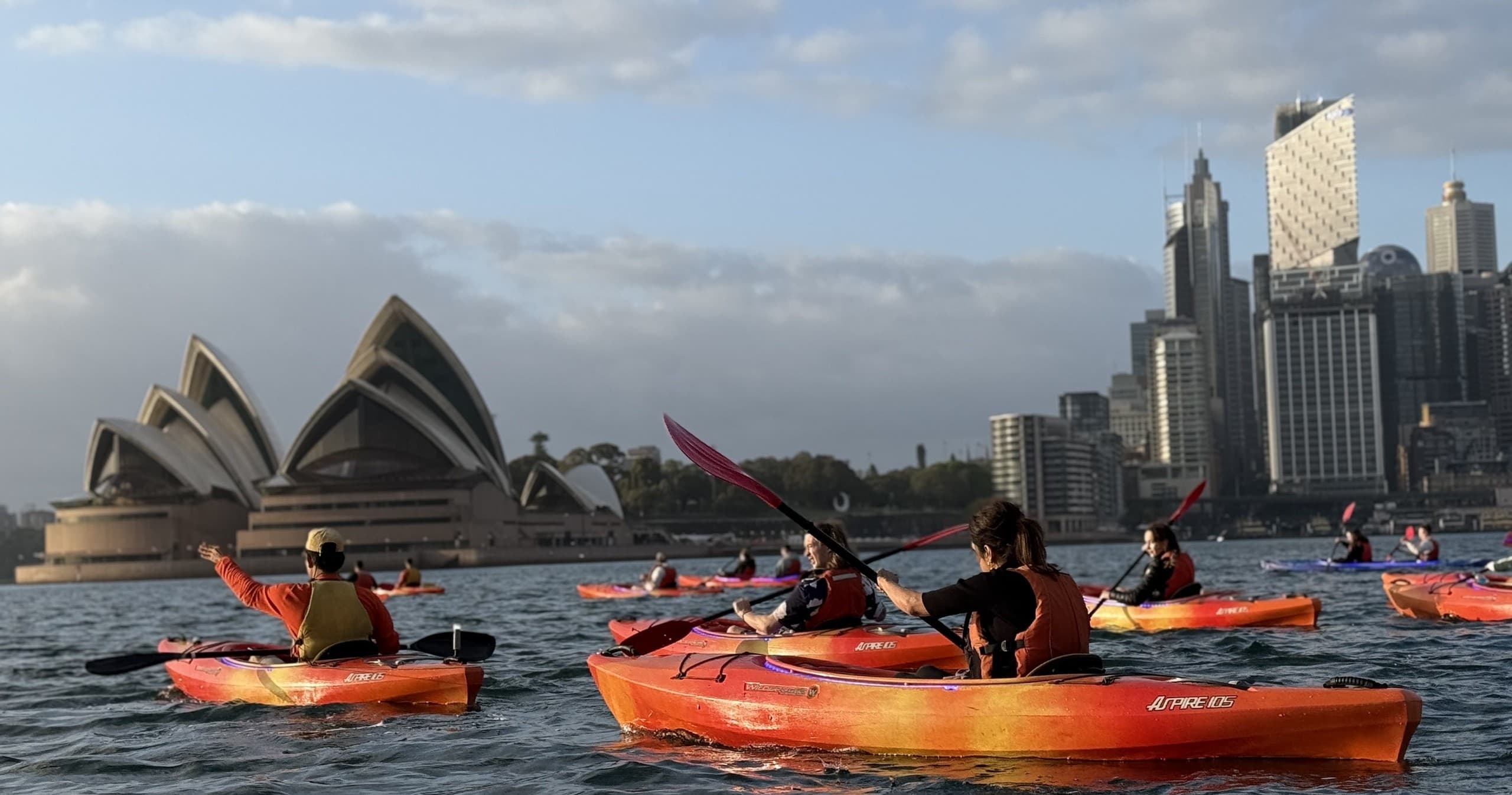 Group kayaking past Sydney Opera House on calm harbour waters