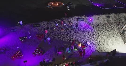 Nighttime beach event with illuminated games and purple party lighting