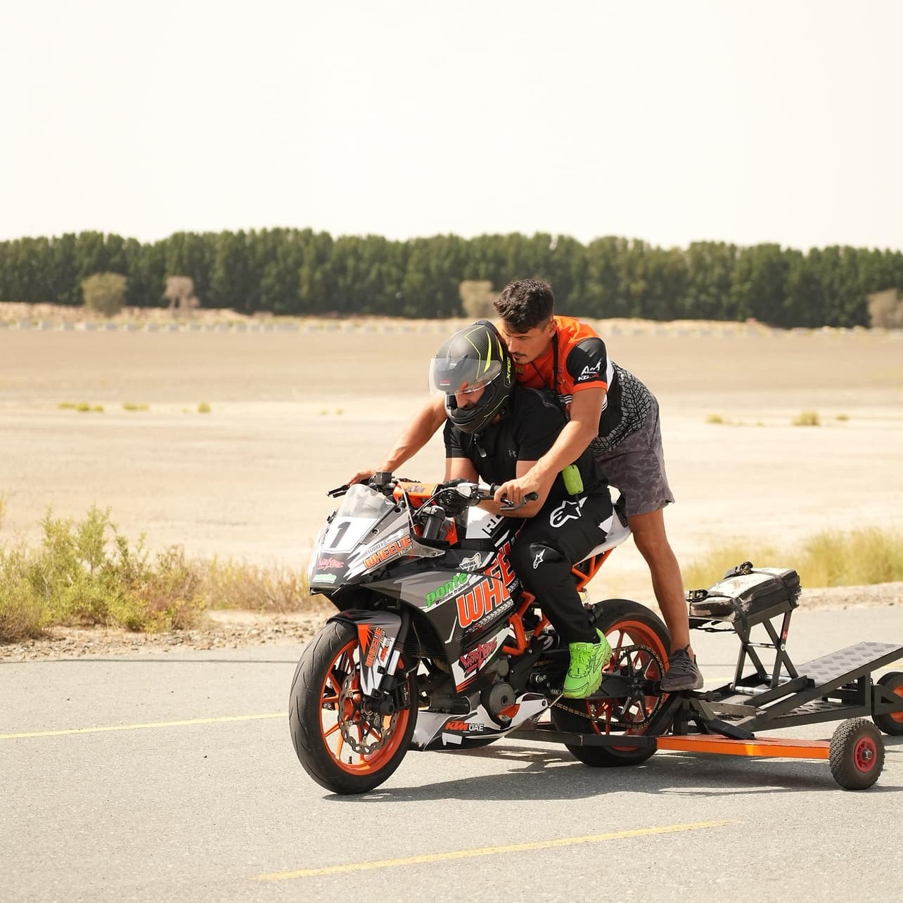 Rider prepping sport motorcycle for stunts on desert road