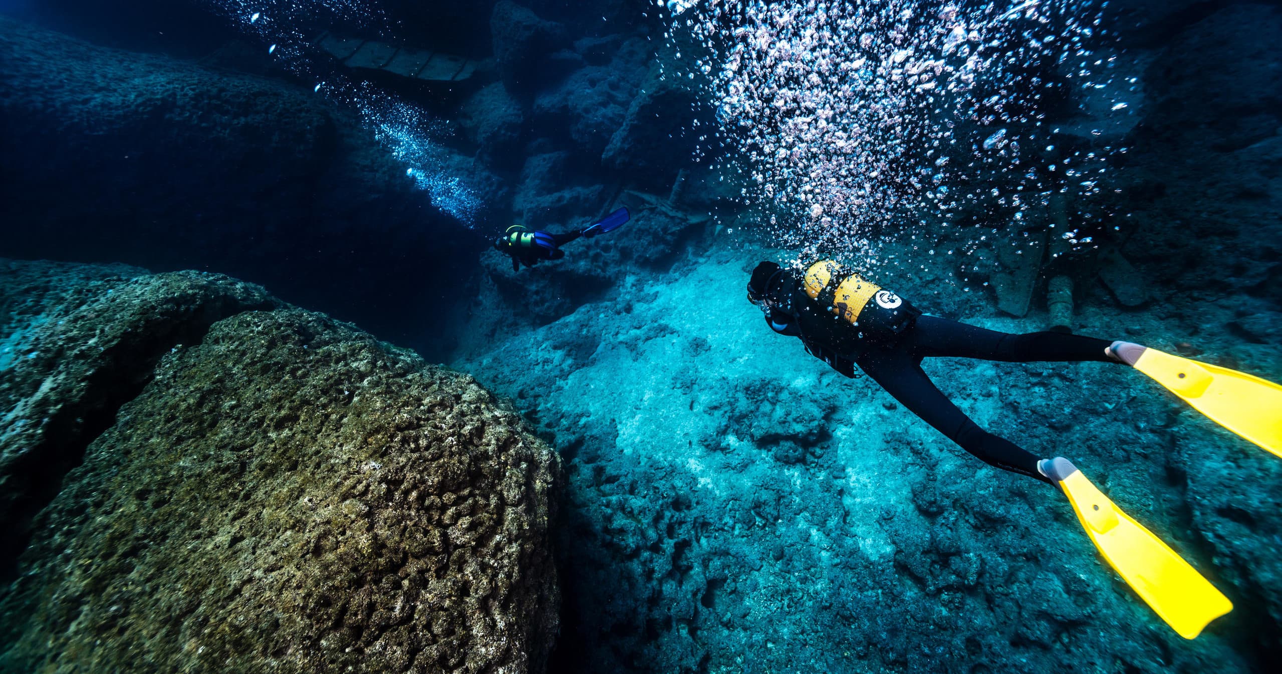 Reef scuba diver with yellow fins exploring clear tropical seafloor