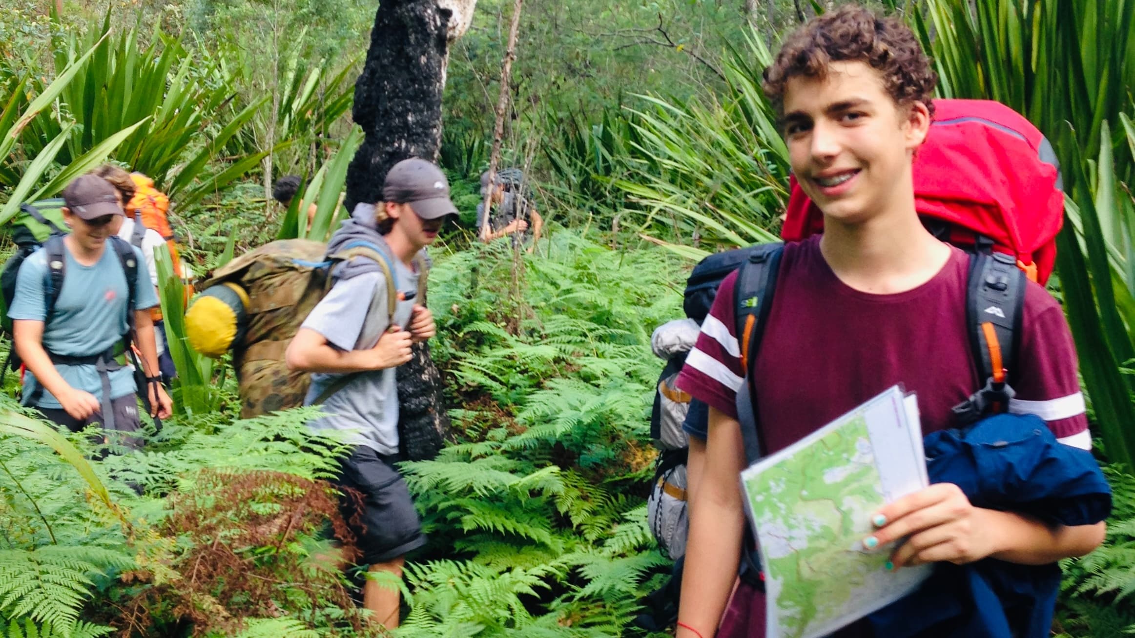 Young hikers with map exploring lush fern bushland on guided walk