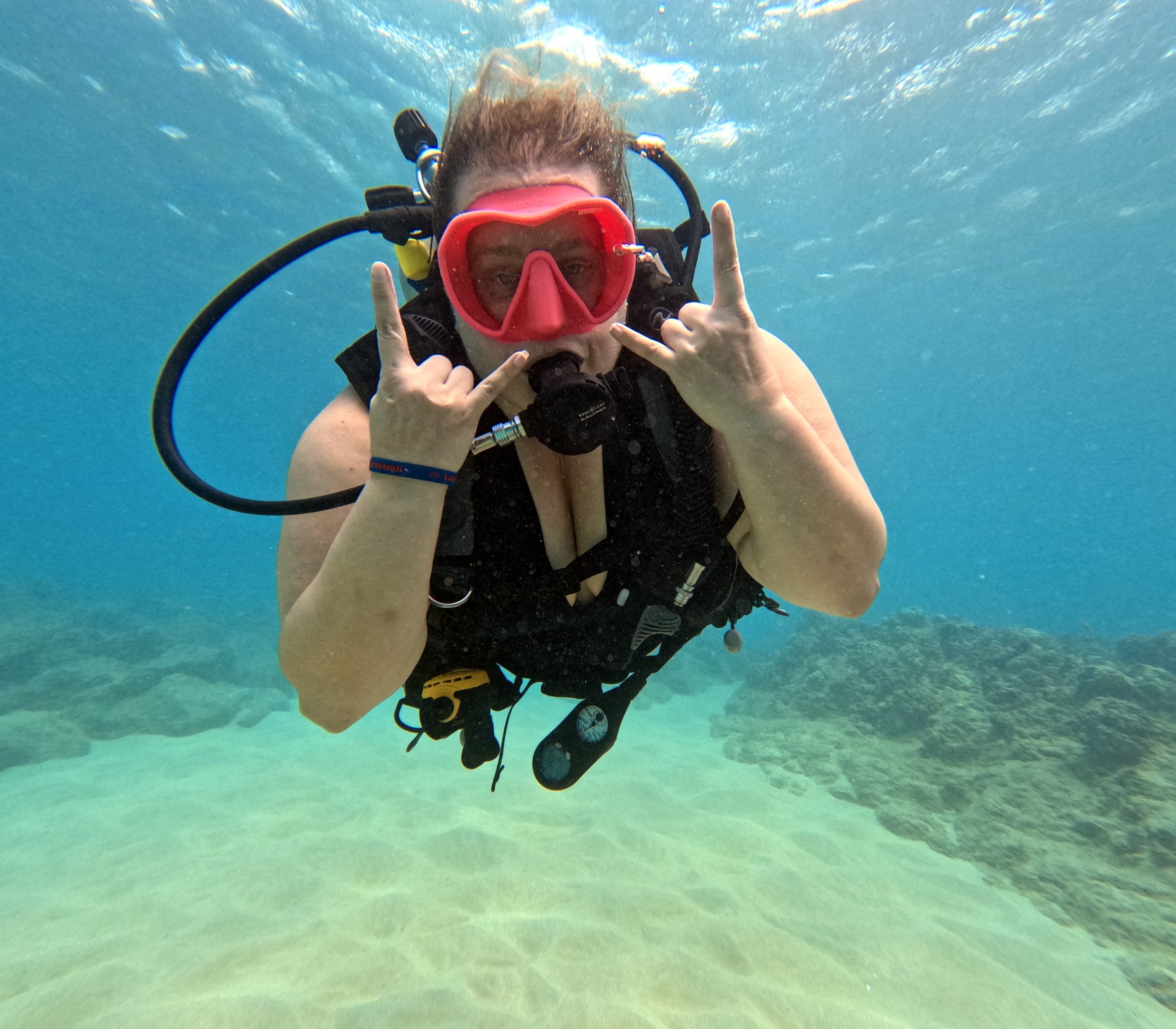 Scuba diver posing underwater over sandy seabed in Hawaii