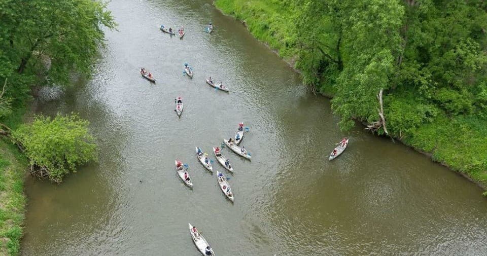 Aerial view of canoeists paddling down a tree-lined river