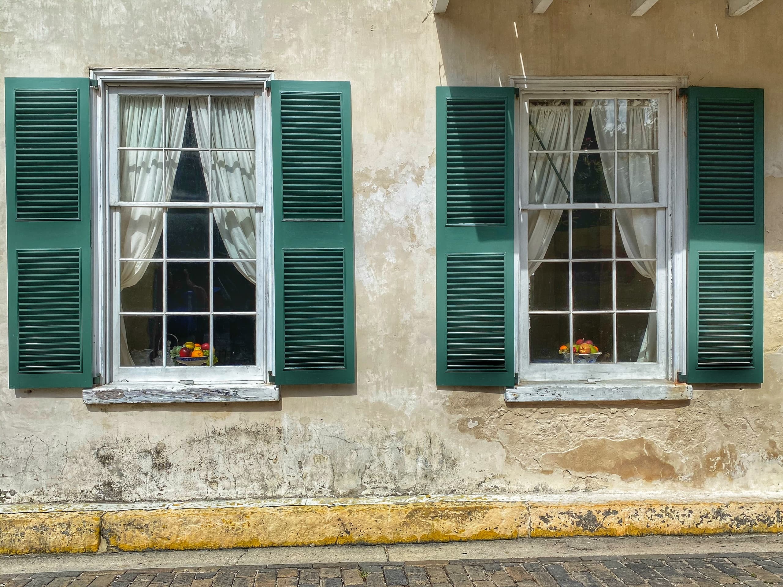 Weathered colonial windows with green shutters on historic St. Augustine street