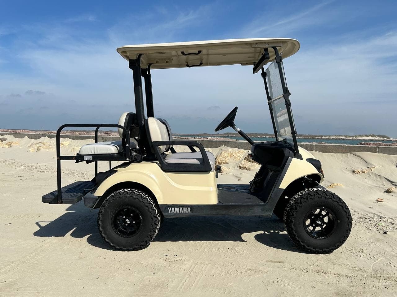 Cream off-road golf cart on sandy dunes for beach access