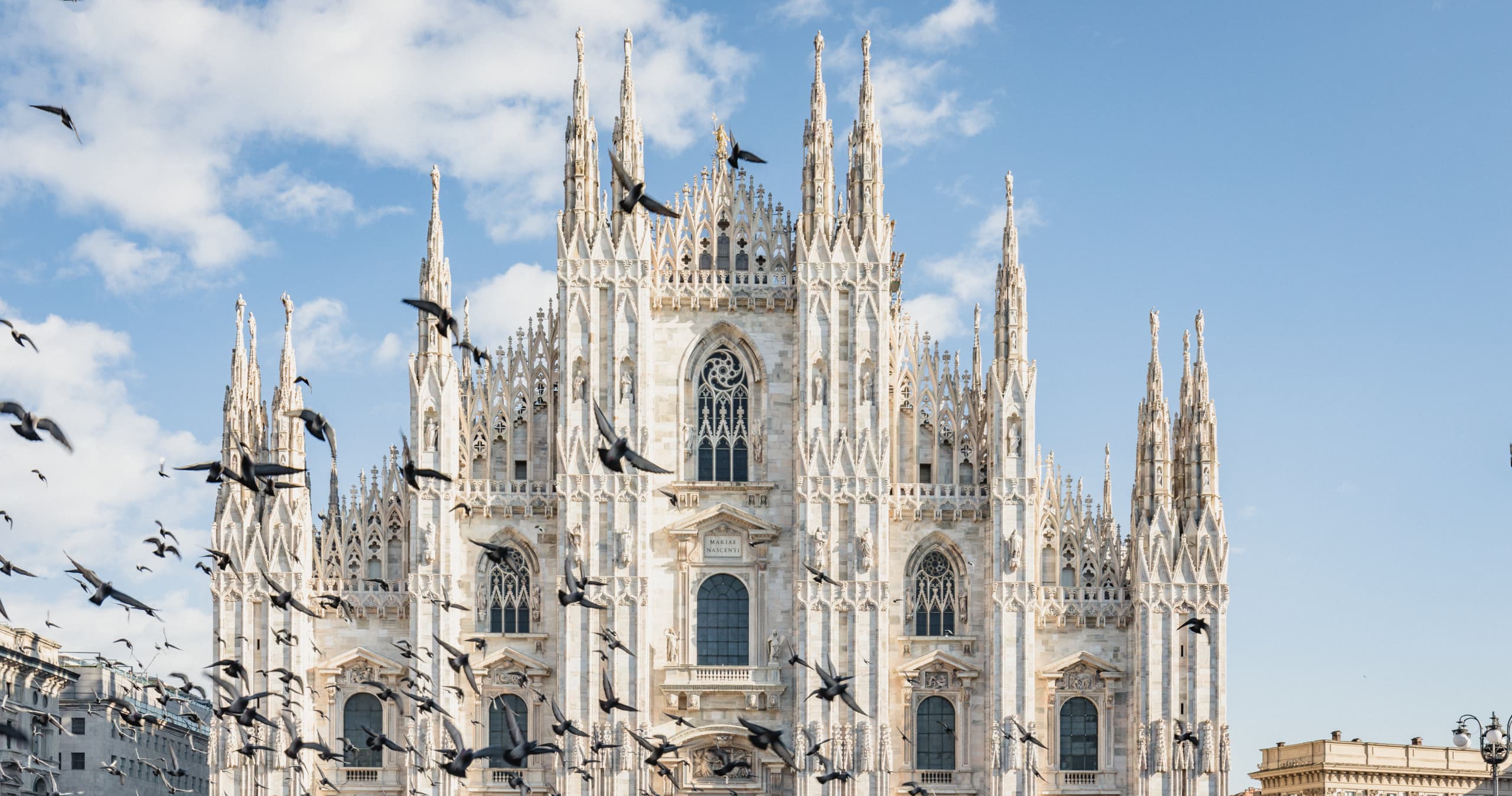 Sunlit Milan Duomo facade with blue sky, tourist landmark