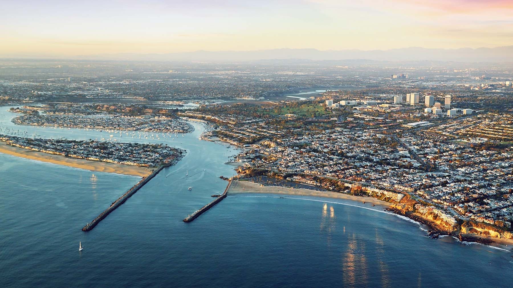 Aerial sightseeing over harbor entrance and coastal city shoreline