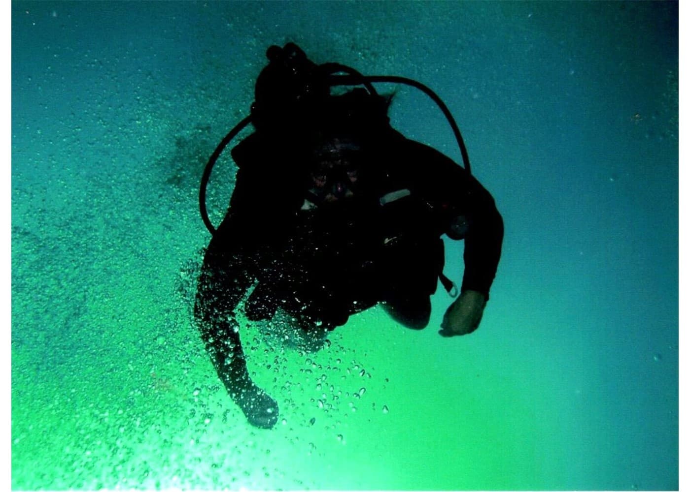 Scuba diver silhouette underwater with green light, deep dive