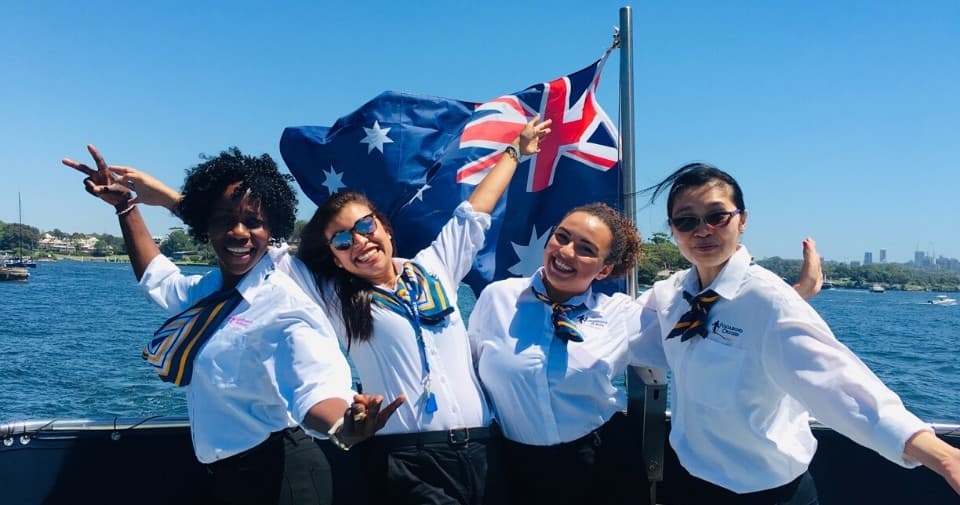 Group waving Australian flag on boat tour across harbor waters