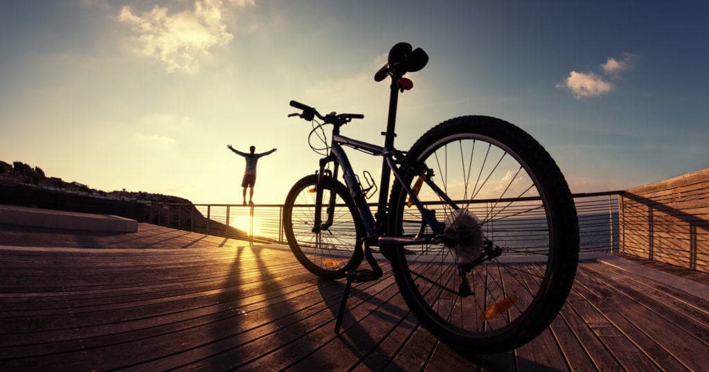 Cyclists silhouetted at sunset on coastal boardwalk celebrating ride