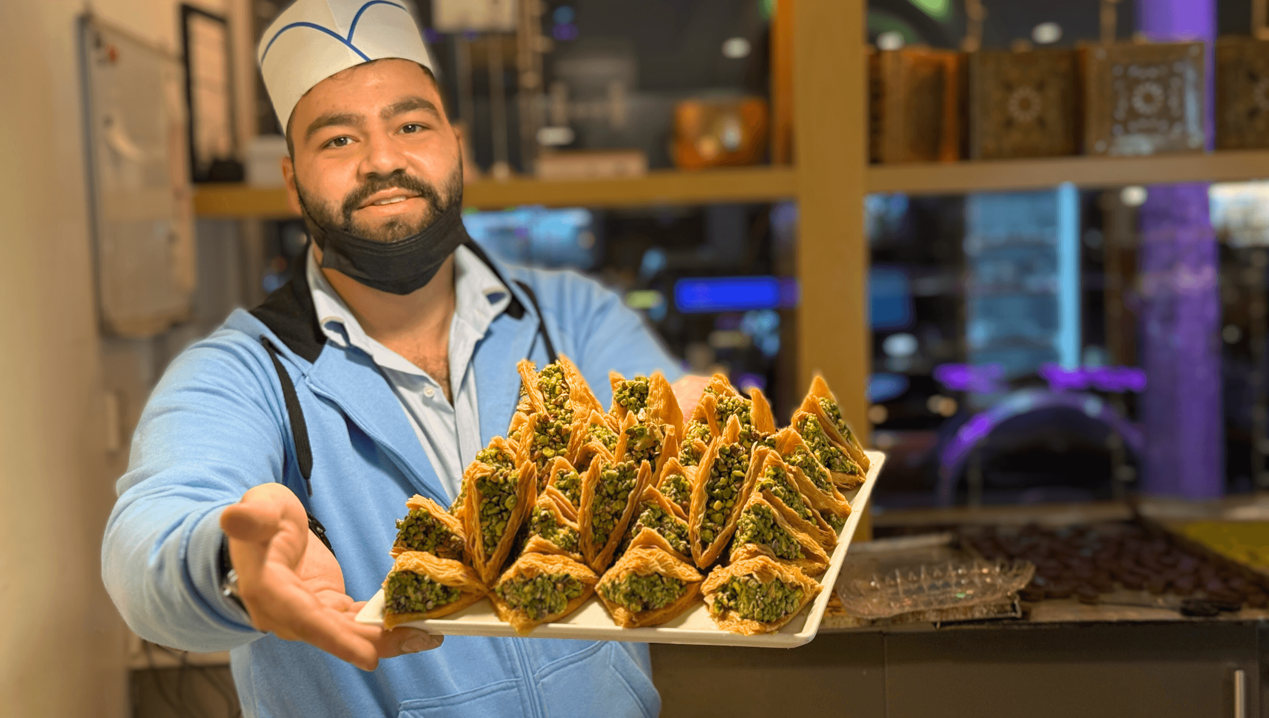 Vendor offering tray of fresh triangular pastries at a market stall