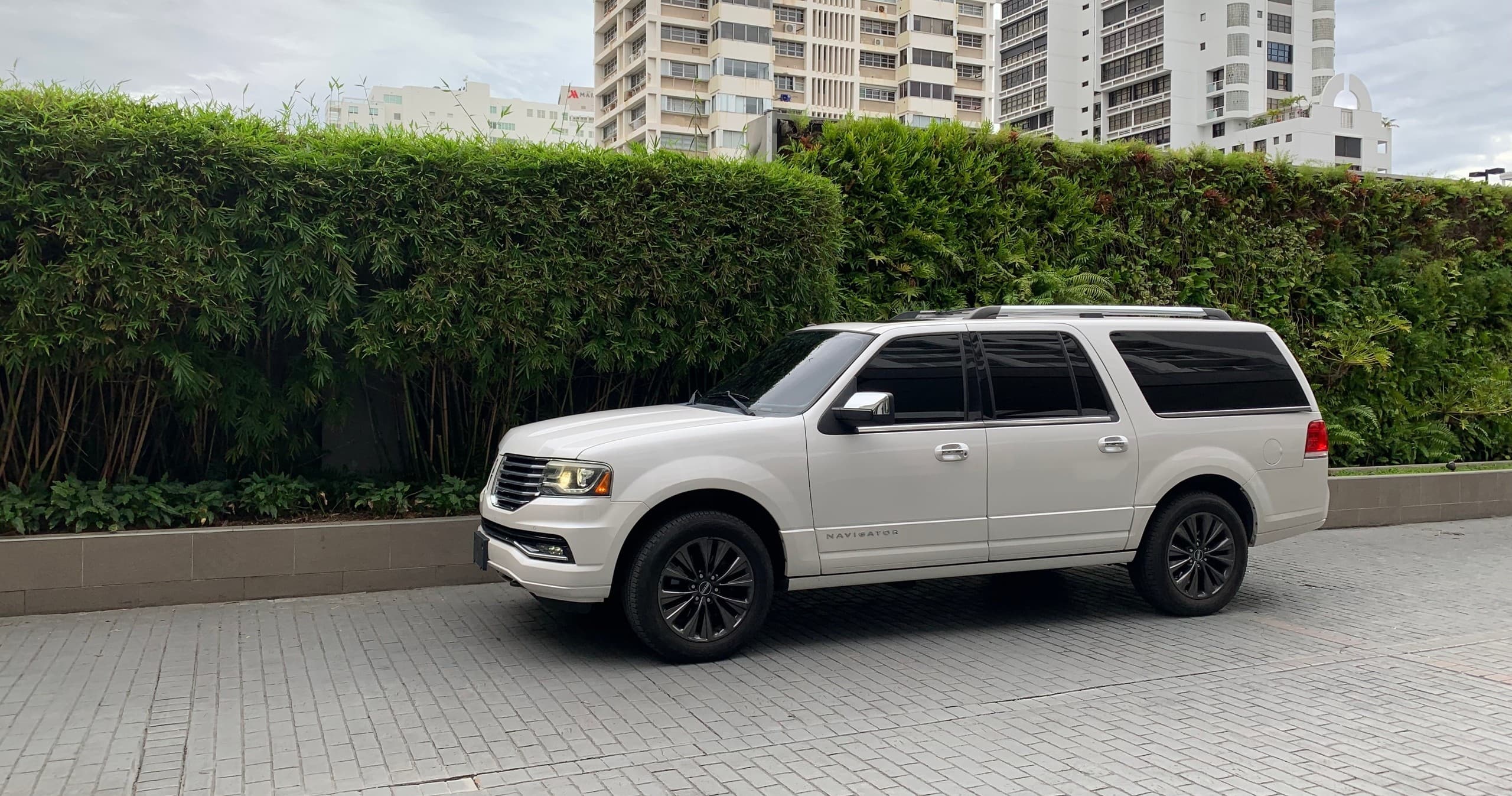 White SUV parked by landscaped hedge near urban residences