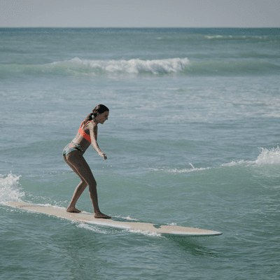 Female surfer riding a small wave along tropical shoreline