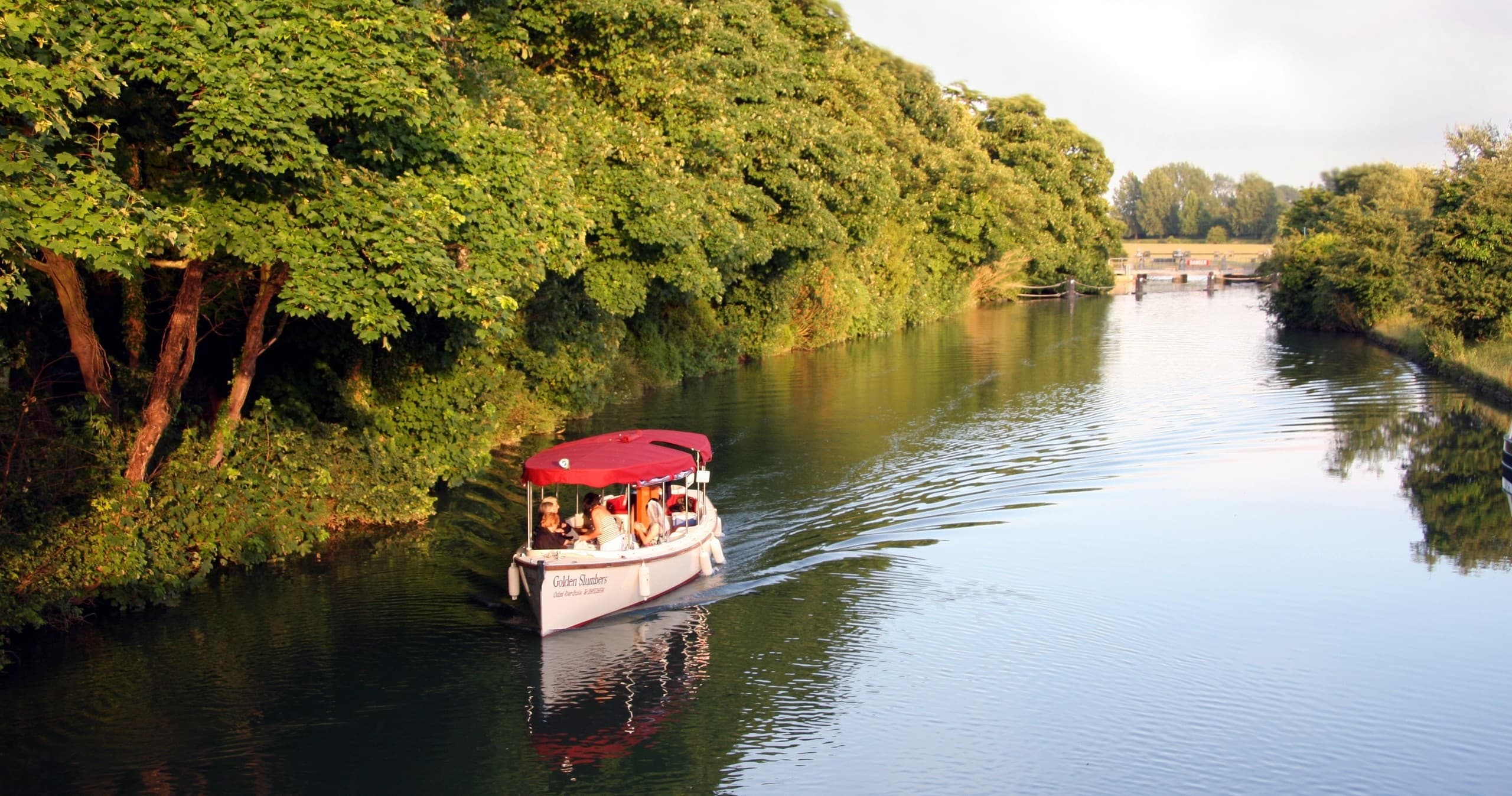 Small passenger boat cruising scenic River Thames near Oxford