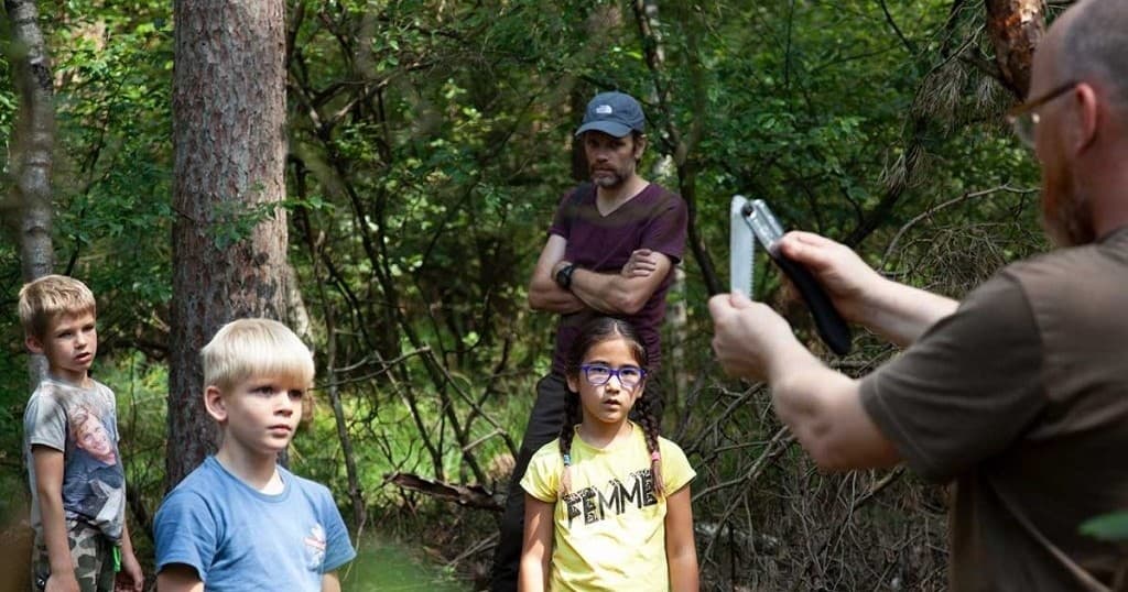 Instructor teaching children nature skills on a forest trail outing