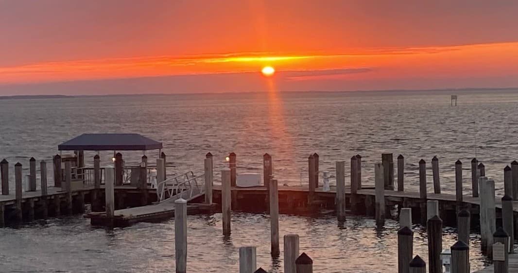 Sunset over dock pilings and calm gulf waters, scenic pier