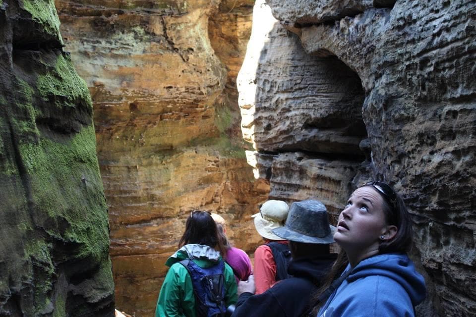 Group exploring narrow sandstone canyon with towering walls