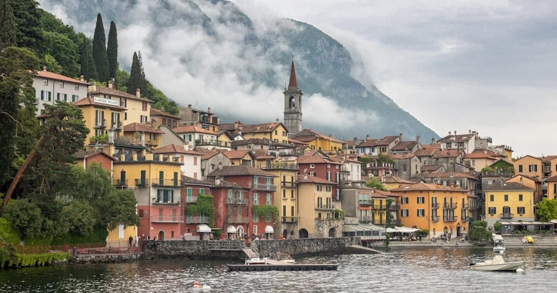 Colorful lakeside village with boats and misty mountain backdrop