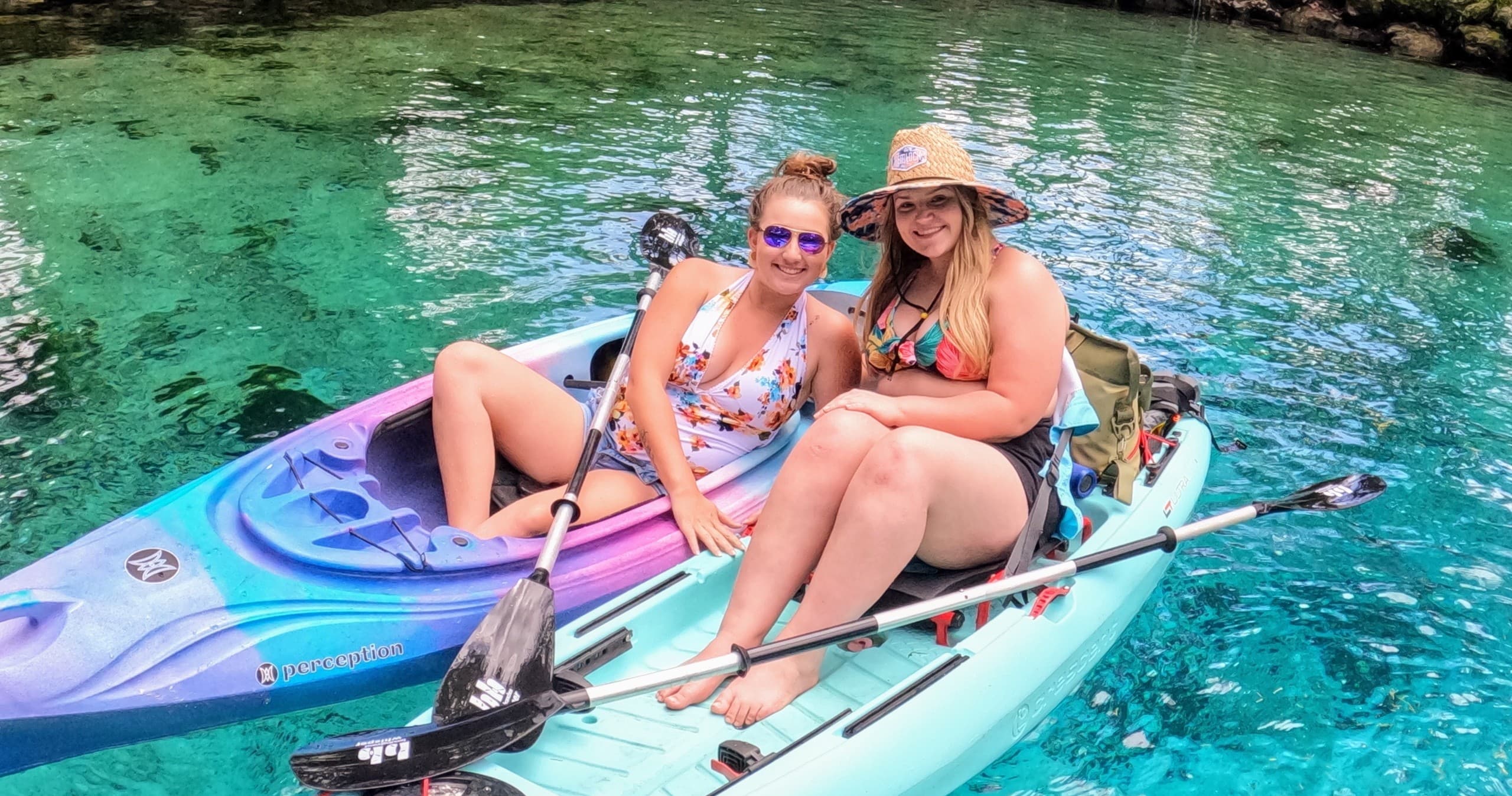 Two women kayaking together on turquoise spring run, sunny day