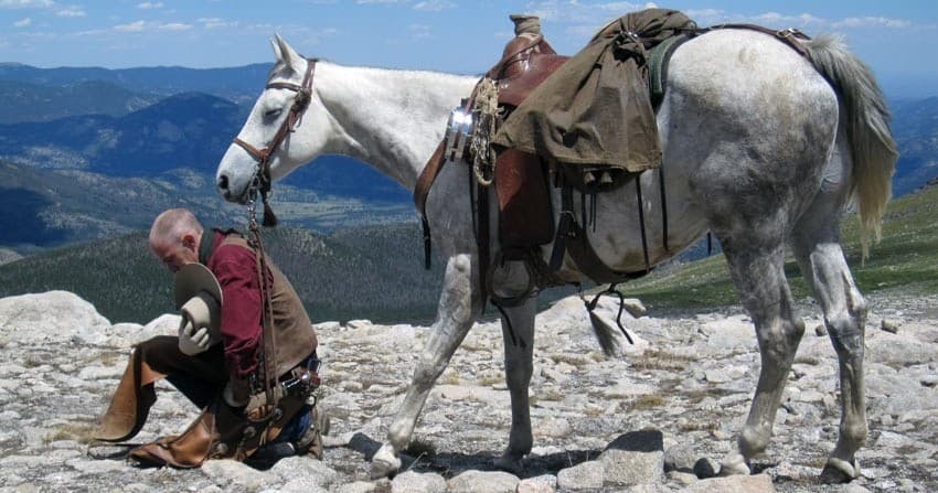 Packhorse and rider resting on rocky alpine ridge with view