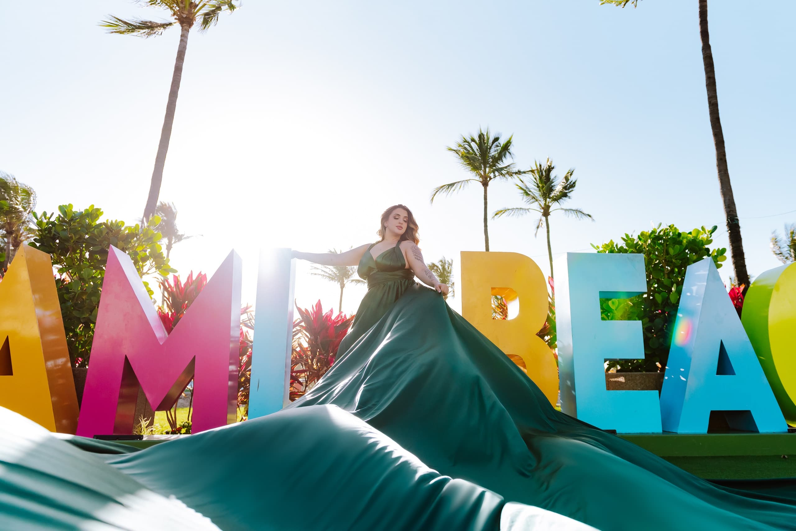 Model posing with Miami Beach sign and flowing gown