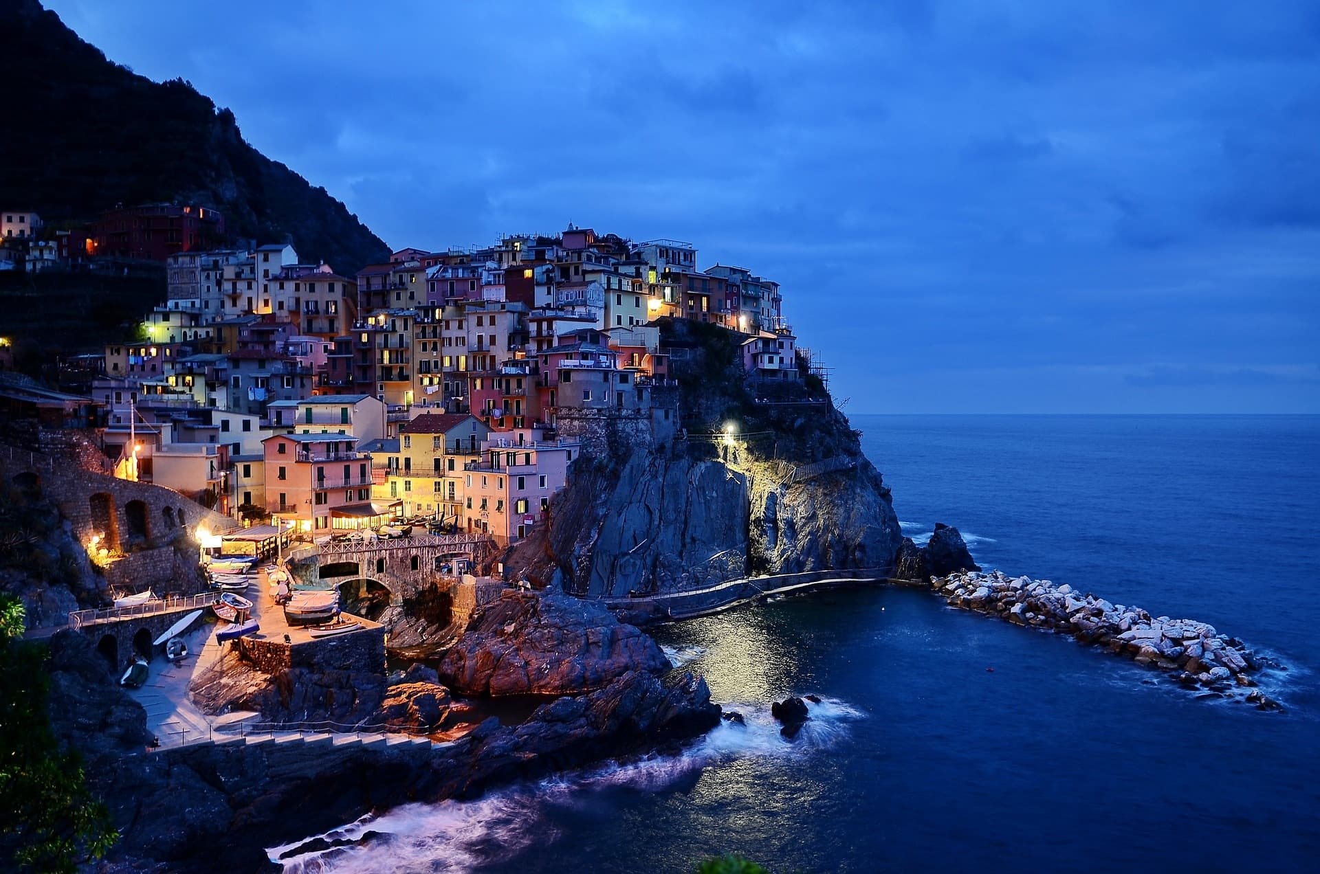 Evening panorama of seaside village and lit harbor cliffs