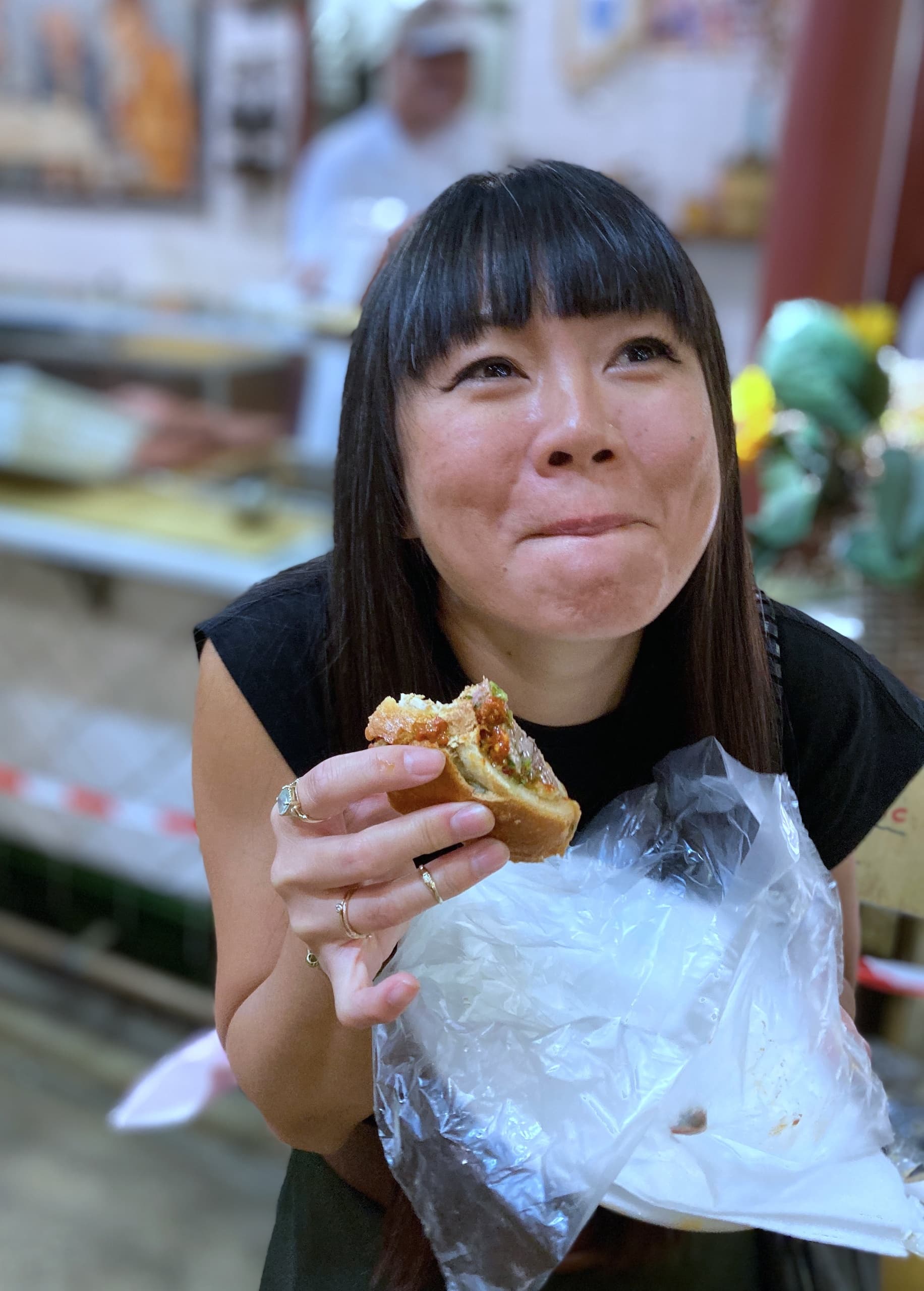 Woman enjoying street food sandwich at lively Italian market