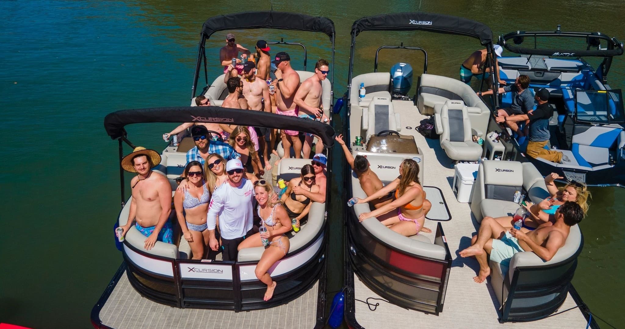 Group relaxing on linked pontoon boats on green lake waters