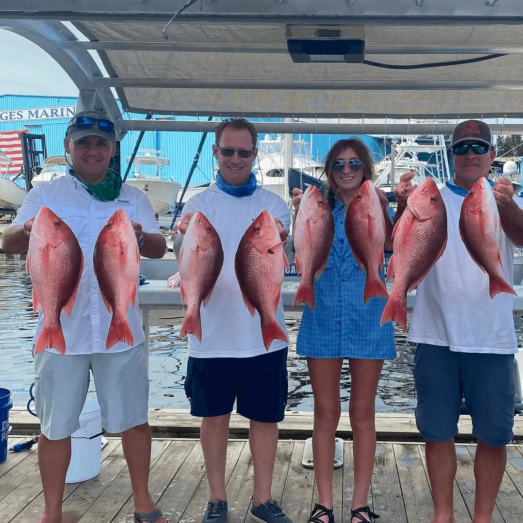 Anglers holding red snapper on marina dock after saltwater charter