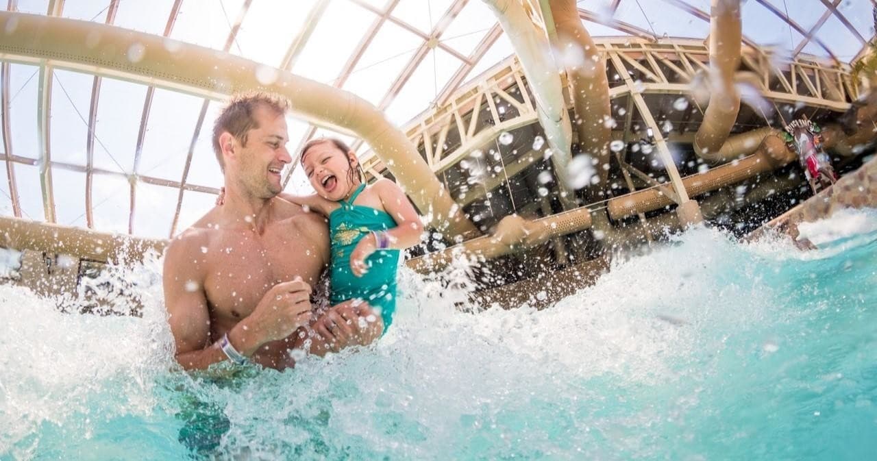Father and child playing in indoor wave pool at resort