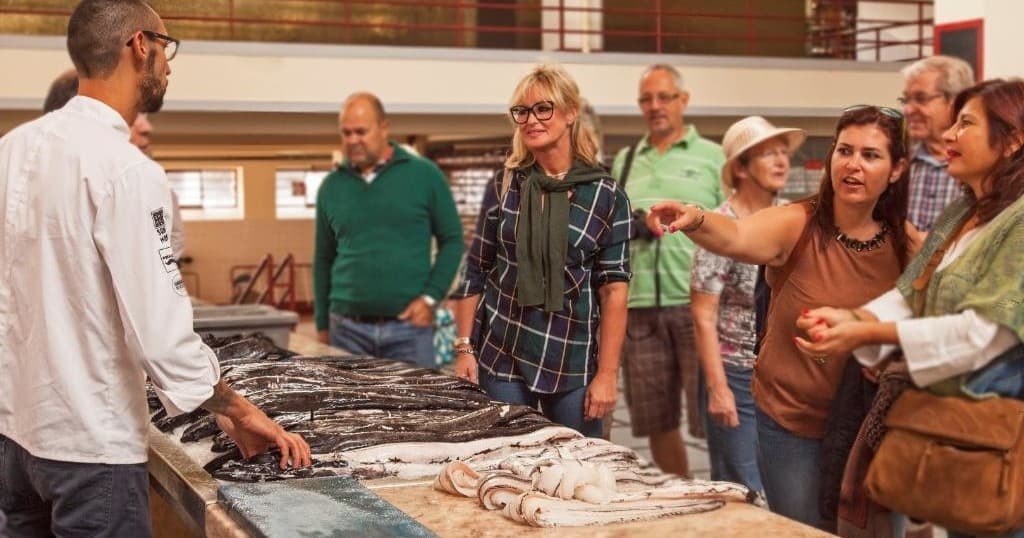 Guide leading fish market tour with shoppers at Madeira market