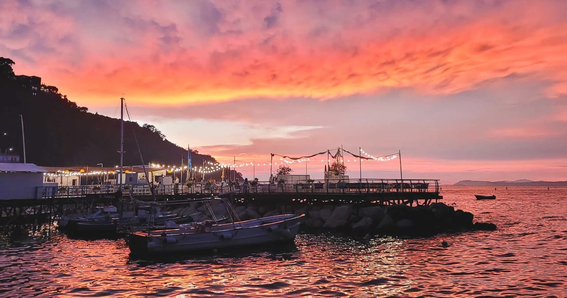 Harbor pier and moored boats at vibrant sunset on Mediterranean coast