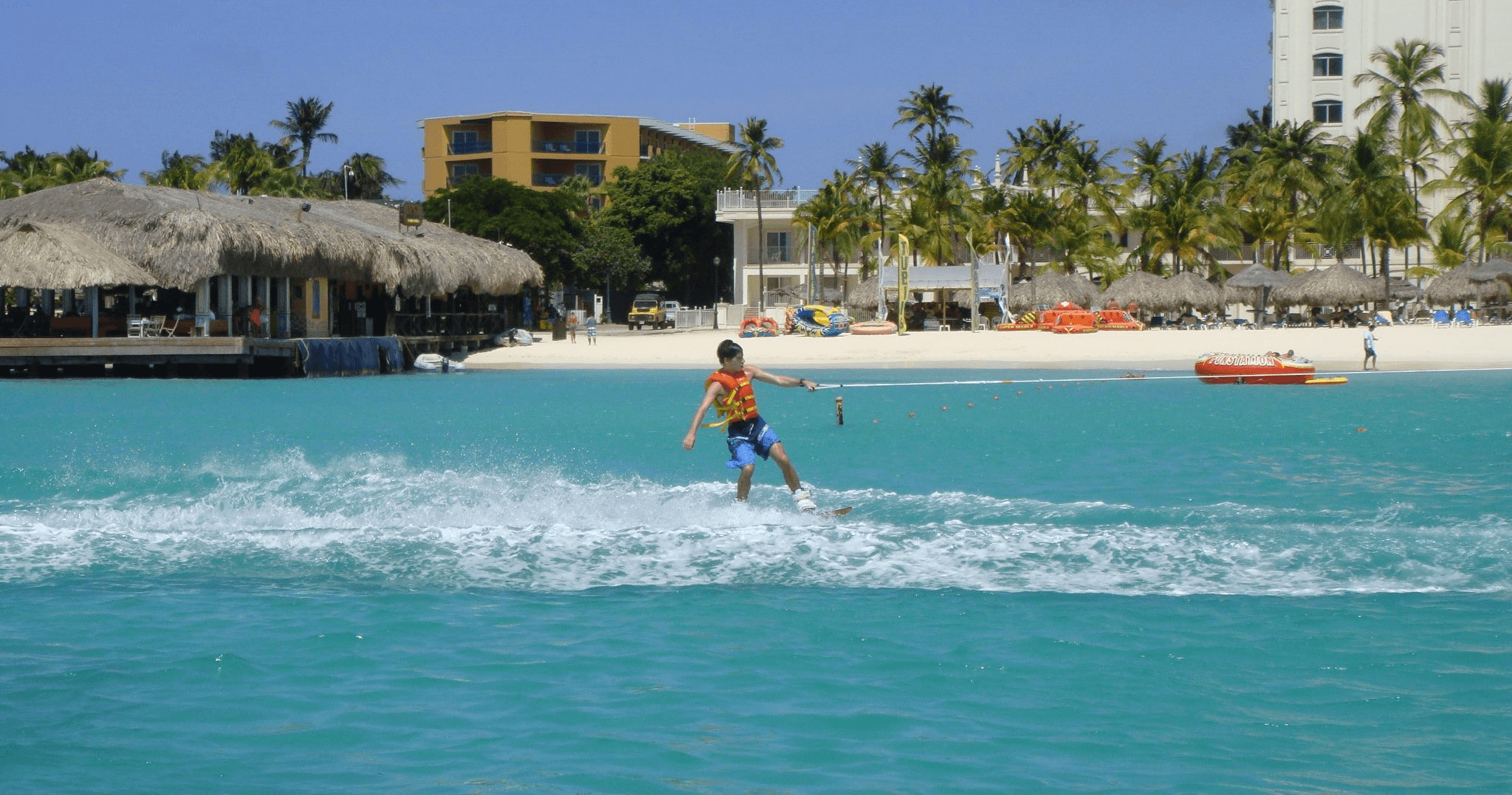 Waterskier carving turquoise surf near Aruba shoreline