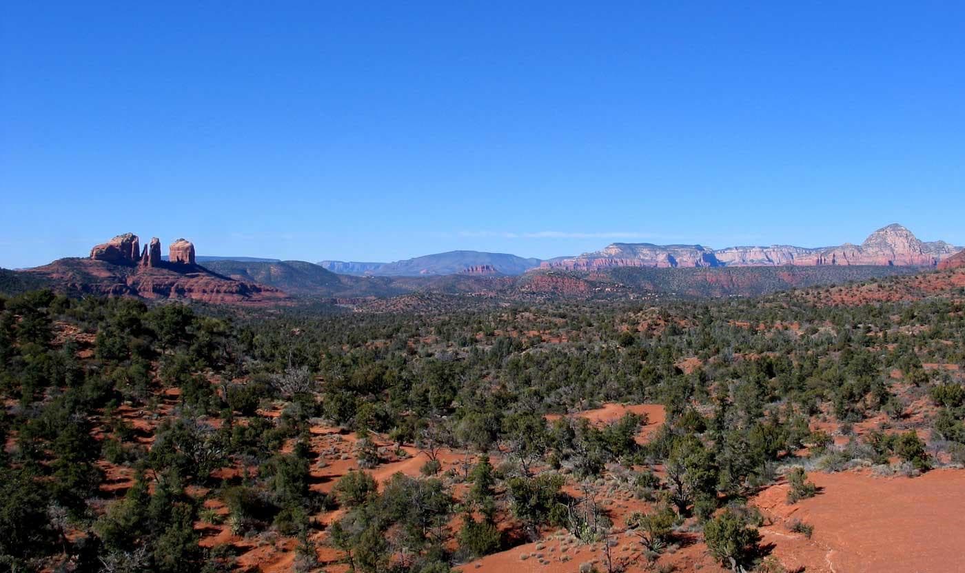 Wide Sedona red‑rock panorama featuring mesas and blue sky