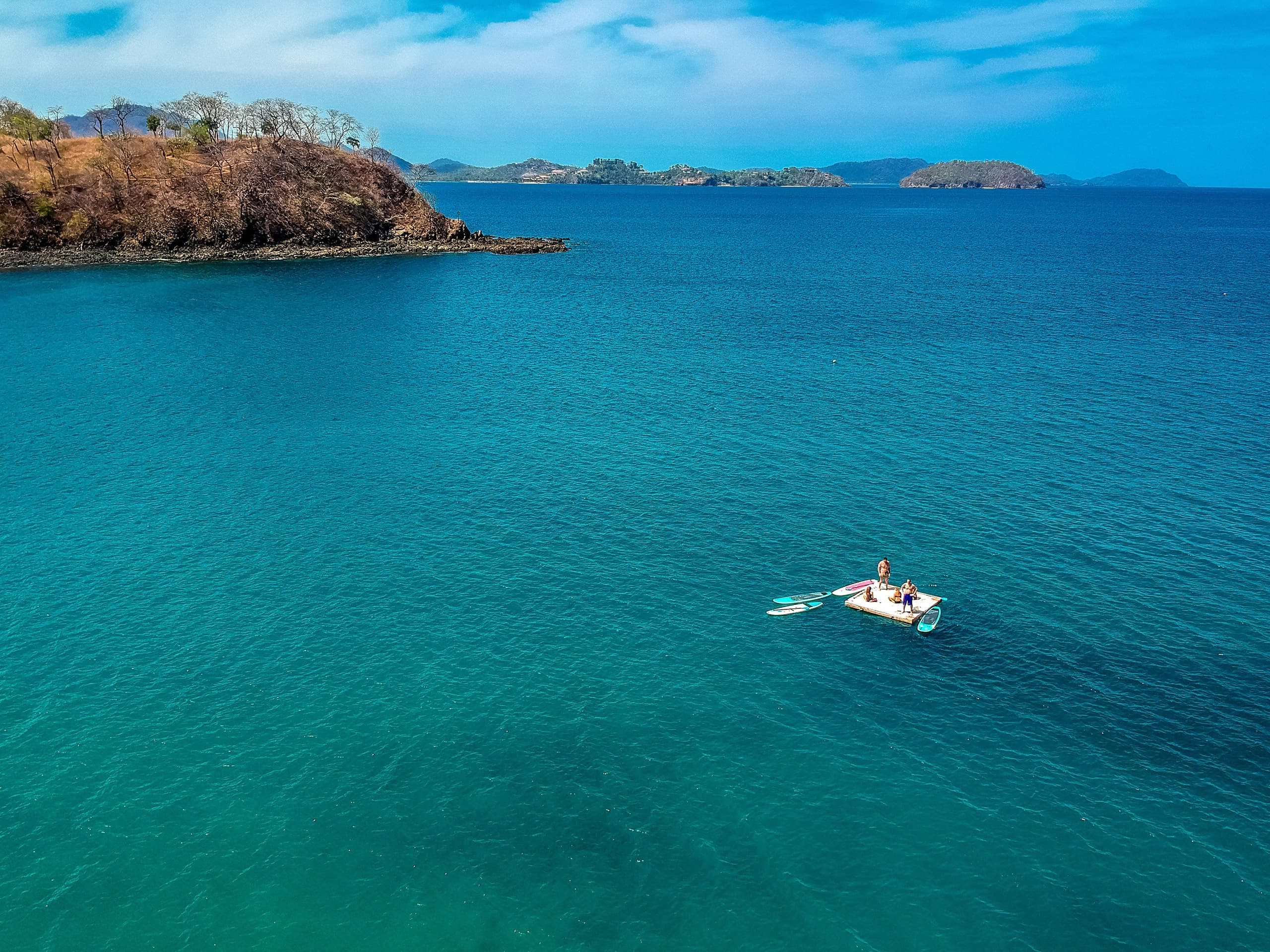 Paddleboarder on turquoise open ocean near tropical islands