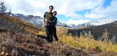 Couple standing on alpine tundra with distant snowy peaks