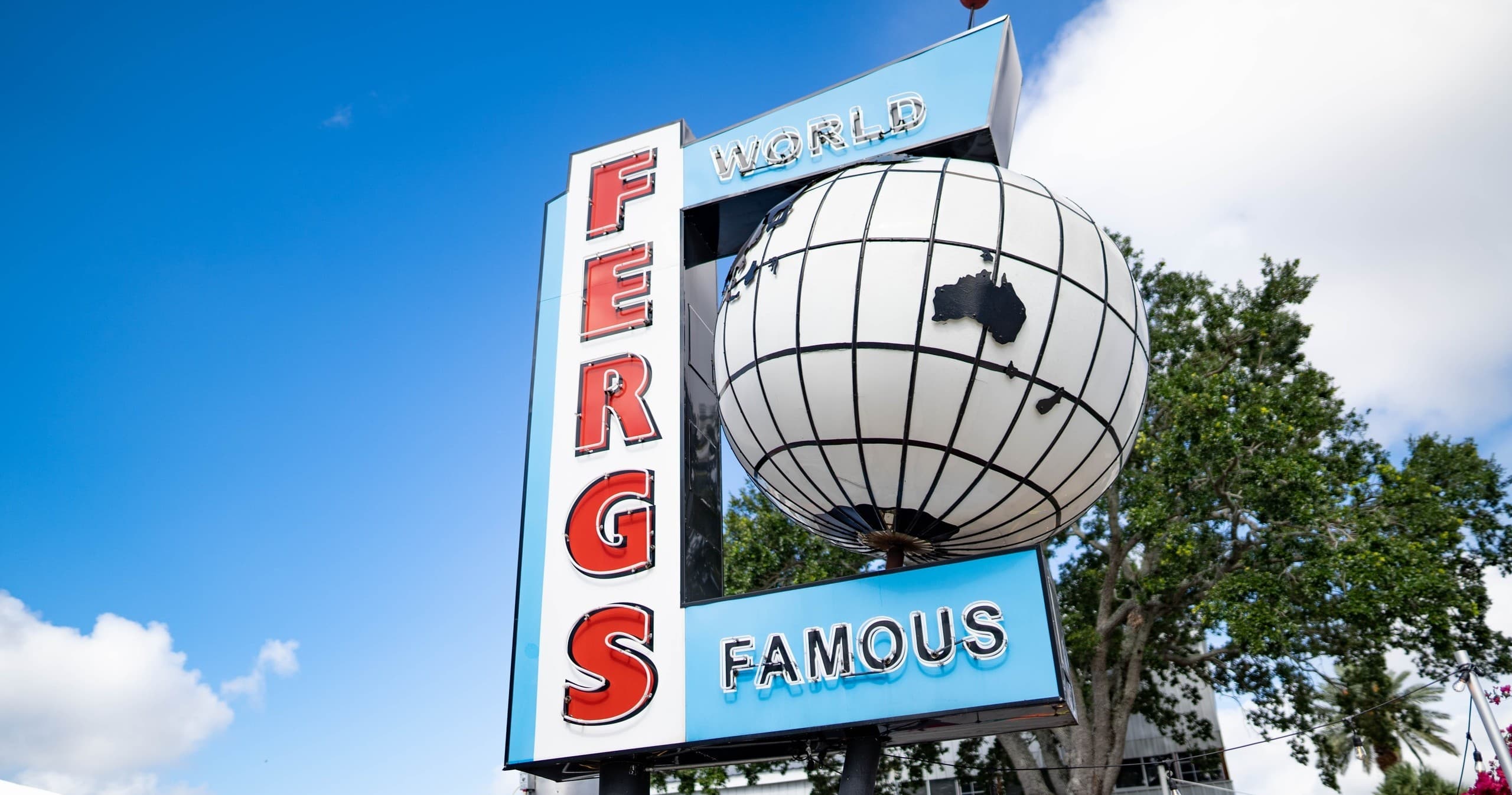 Vintage outdoor neon sign advertising Fergs Sports Bar and Grill under blue sky